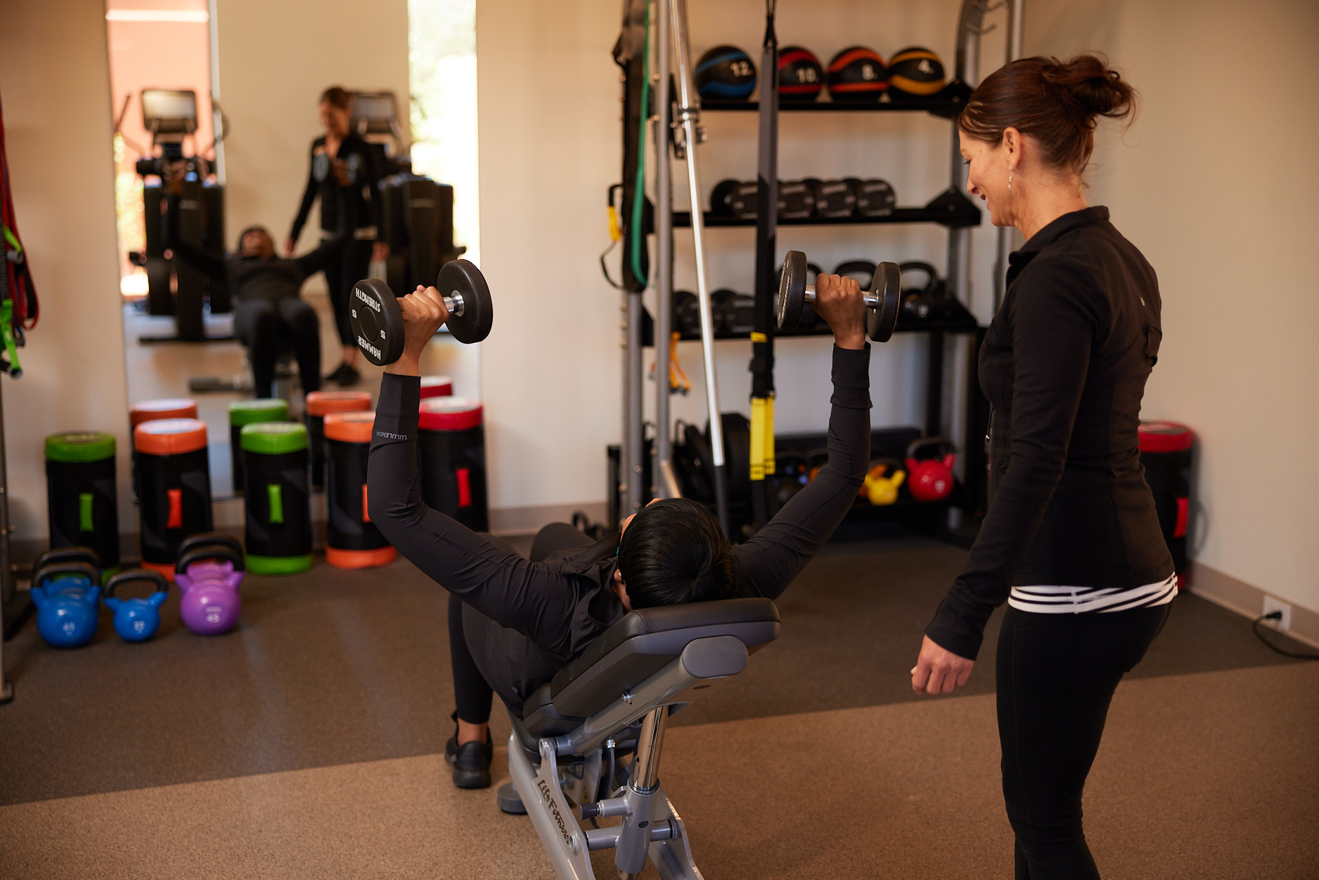 personal coach at Mii amo fitness studio with woman lifting weights
